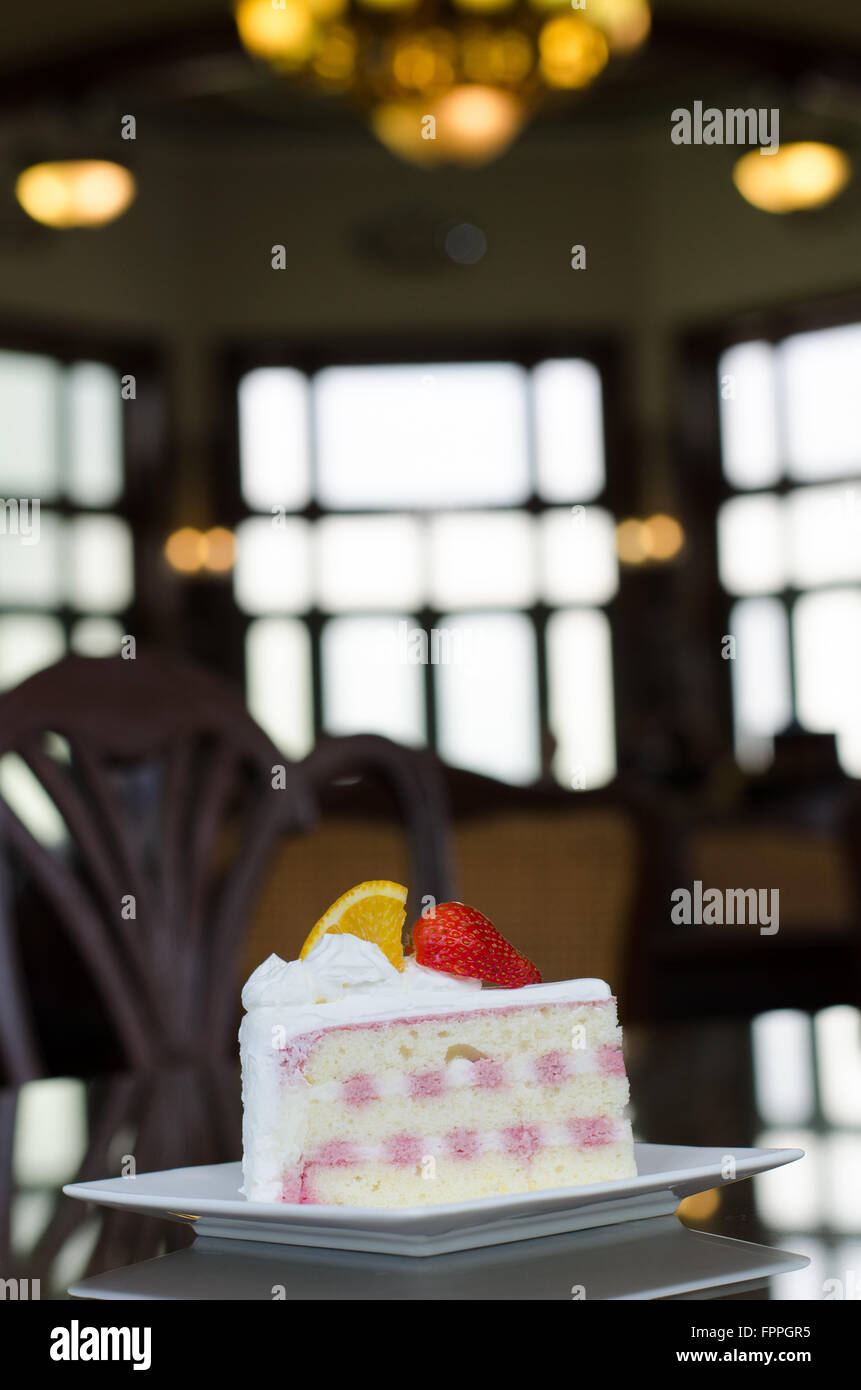 Stück Kuchen mit Pudding-Creme und reife Erdbeeren und Orange auf einem Teller Stockfoto