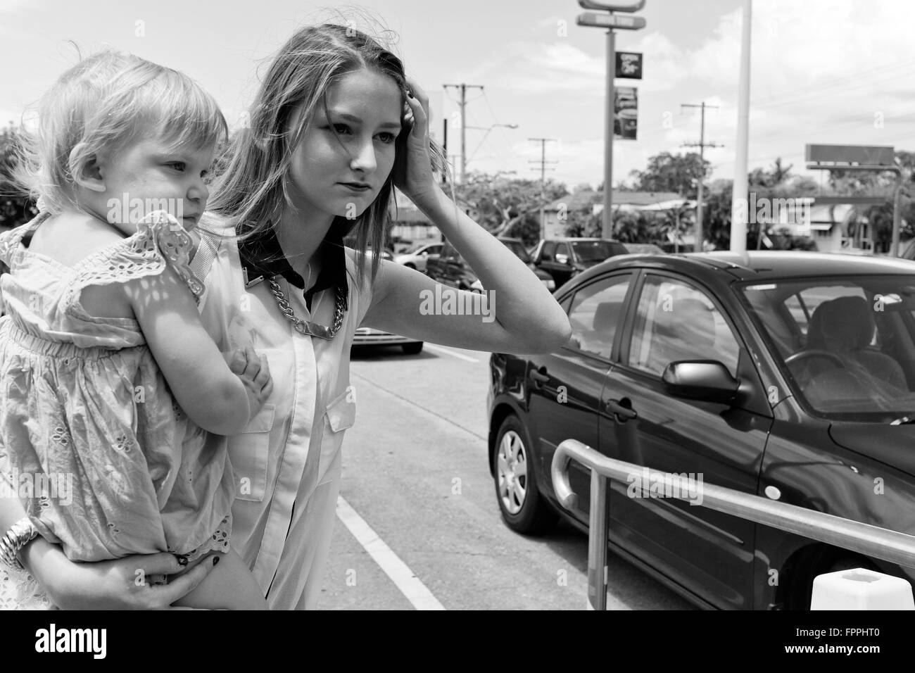 eine junge Mutter mit Baby wartet überqueren eine viel befahrenen Straße in Brisbane, Queensland, Australien Stockfoto