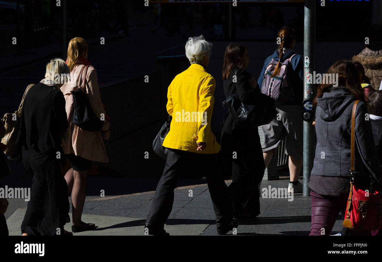 am frühen Morgen Sonnenlicht trifft Pendler in gelben Jacke in einer ansonsten tristen Umgebung in Brisbane Cbd Australien im Berufsverkehr Stockfoto