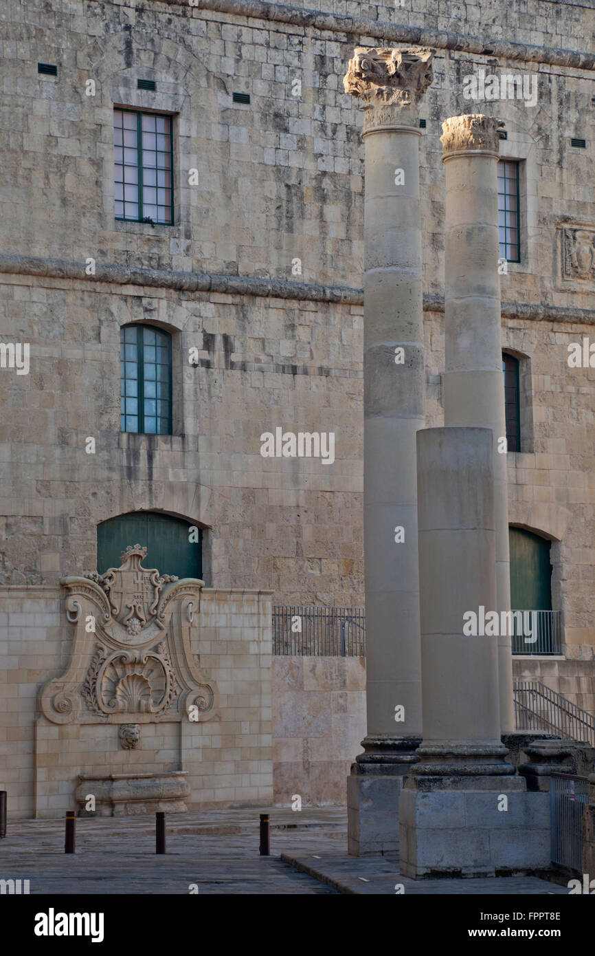 Drei eigenständige Spalten des zerstörten Royal Opera House gegen die verbotene Wände des Kavaliers in Valletta umrahmt. Stockfoto