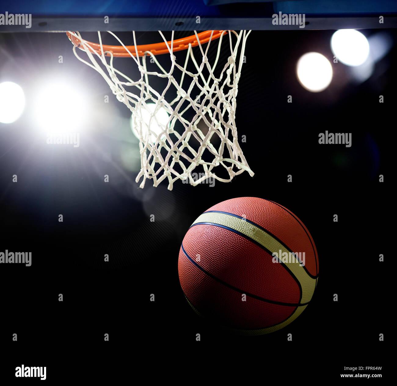 Basketball wird durch den Reifen bei einer Sportarena (vorsätzliche Spotlight) Stockfoto