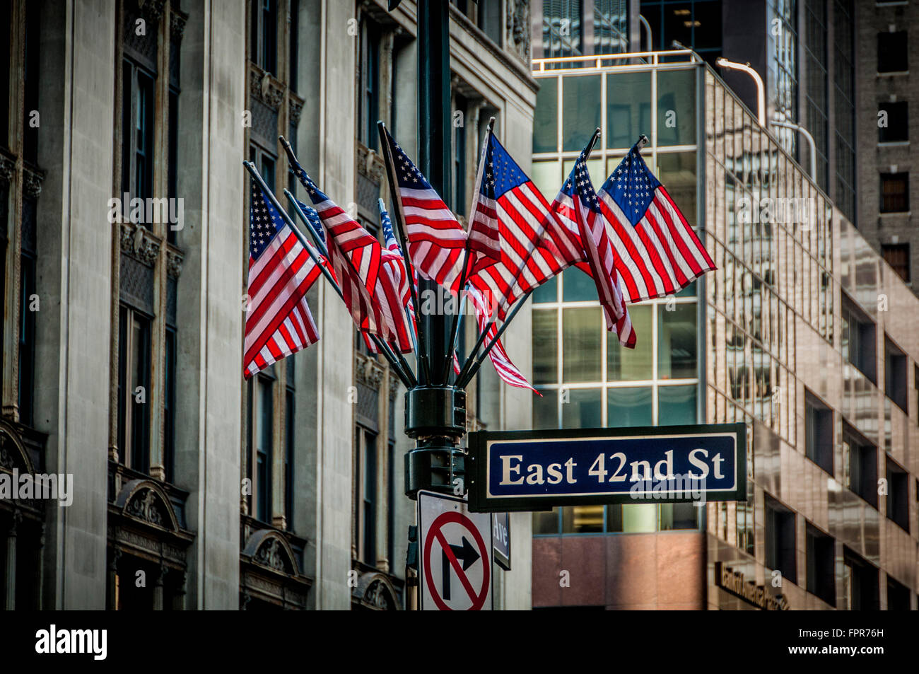 East 42nd St Zeichen und Gruppe von amerikanischen Flaggen auf Laternenpfahl, New York City, USA. Stockfoto