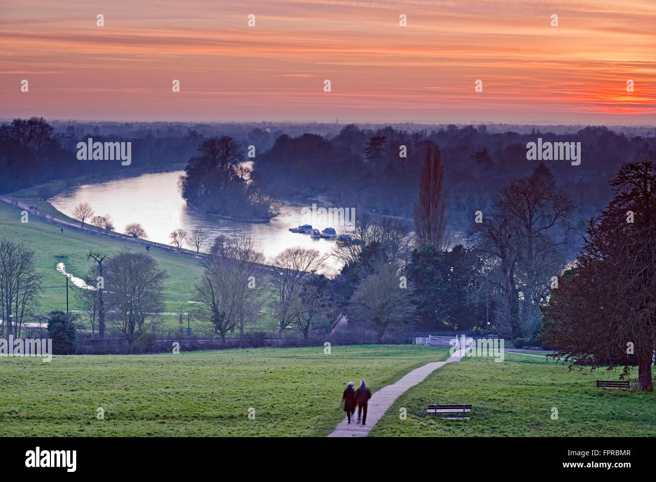 Richmond Hill bei Sonnenuntergang mit der Themse und Petersham Wiesen im Hintergrund und ein Mann und eine Frau zu Fuß entfernt Stockfoto
