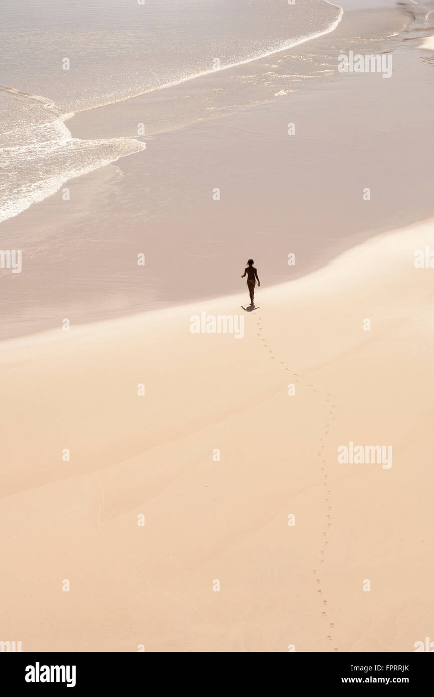 Figur in einer Landschaft. Eine junge Frau an einem einsamen tropischen Strand auf der Insel Fernando de Noronha in Brasilien Stockfoto