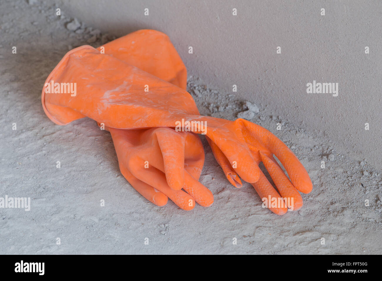 Zwei orange Gummihandschuhe auf konkrete Flloor auf Baustelle Stockfoto