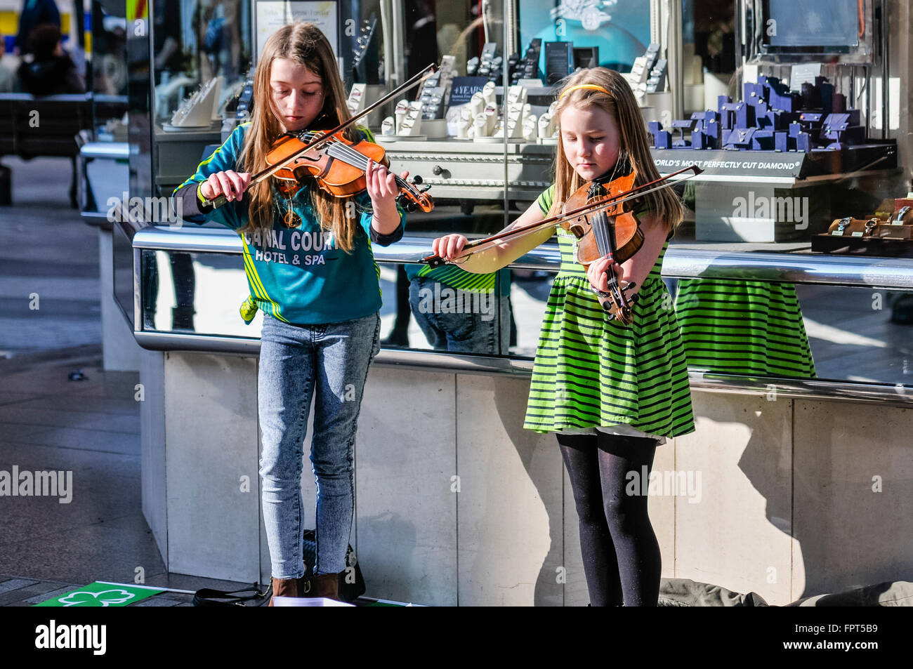 Belfast, Nordirland. 17. März 2016 - busk zwei junge Mädchen durch irische traditionelle Geige Musizieren. Stockfoto