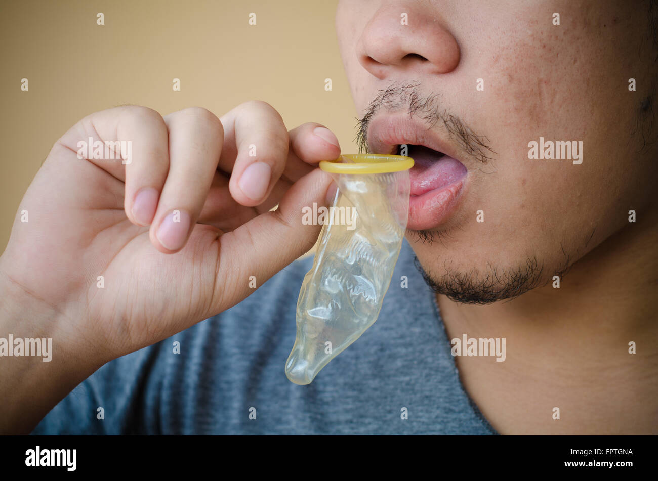 Mund eines jungen Mannes lecken ein Kondom Stockfoto