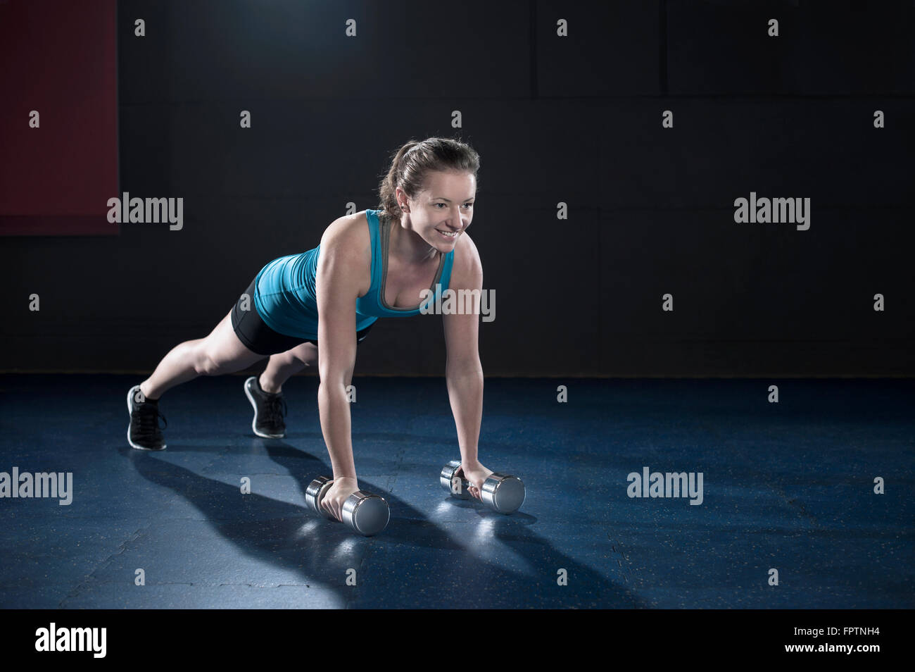 Sportliche junge Frau, die Übung mit Hantel in der Turnhalle, Bayern, Deutschland Stockfoto