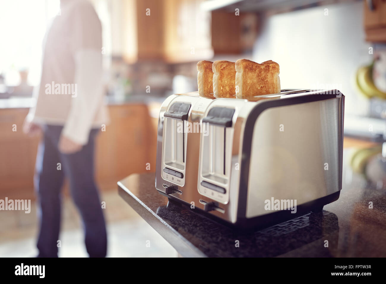 Am frühen Morgen geröstetes Brot, Mann in der Küche und bereitet Toast zum Frühstück bei Sonnenaufgang Stockfoto