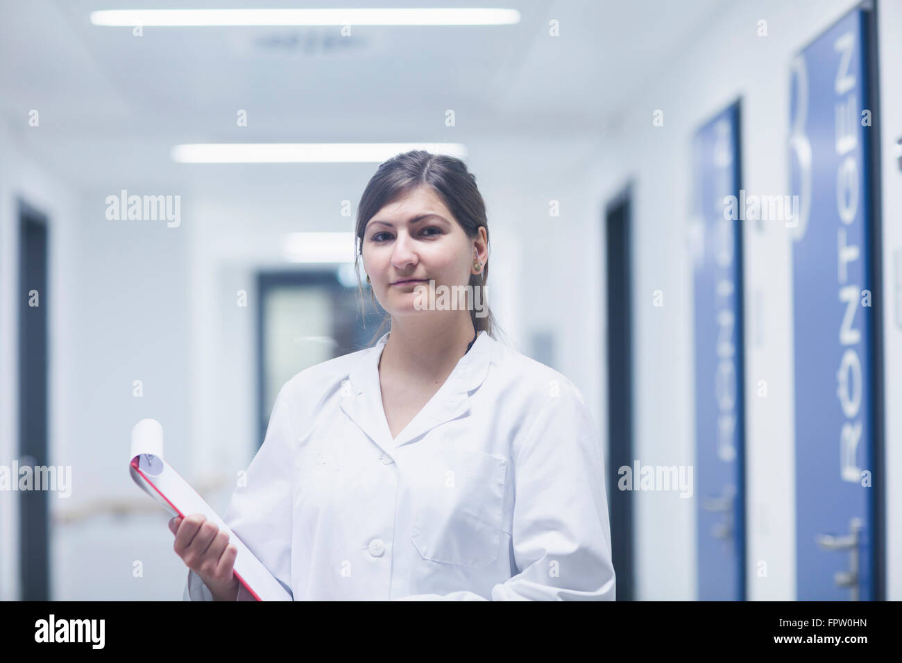 Porträt einer jungen Ärztin hält Zwischenablage im Krankenhausflur, Freiburg Im Breisgau, Baden-Württemberg, Deutschland Stockfoto