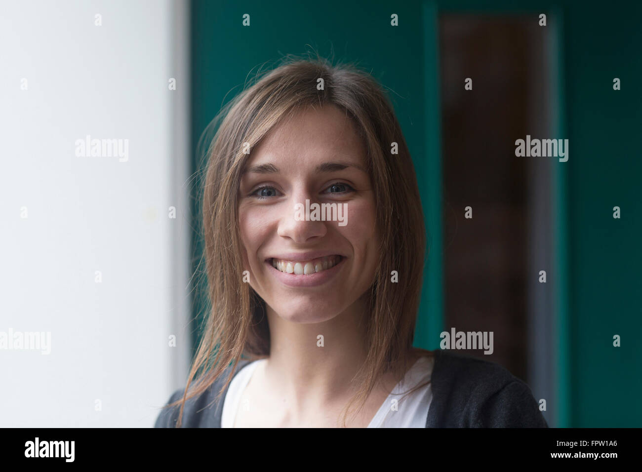 Porträt einer jungen Frau lächelnd vor Haustür, Freiburg Im Breisgau, Baden-Württemberg, Deutschland Stockfoto