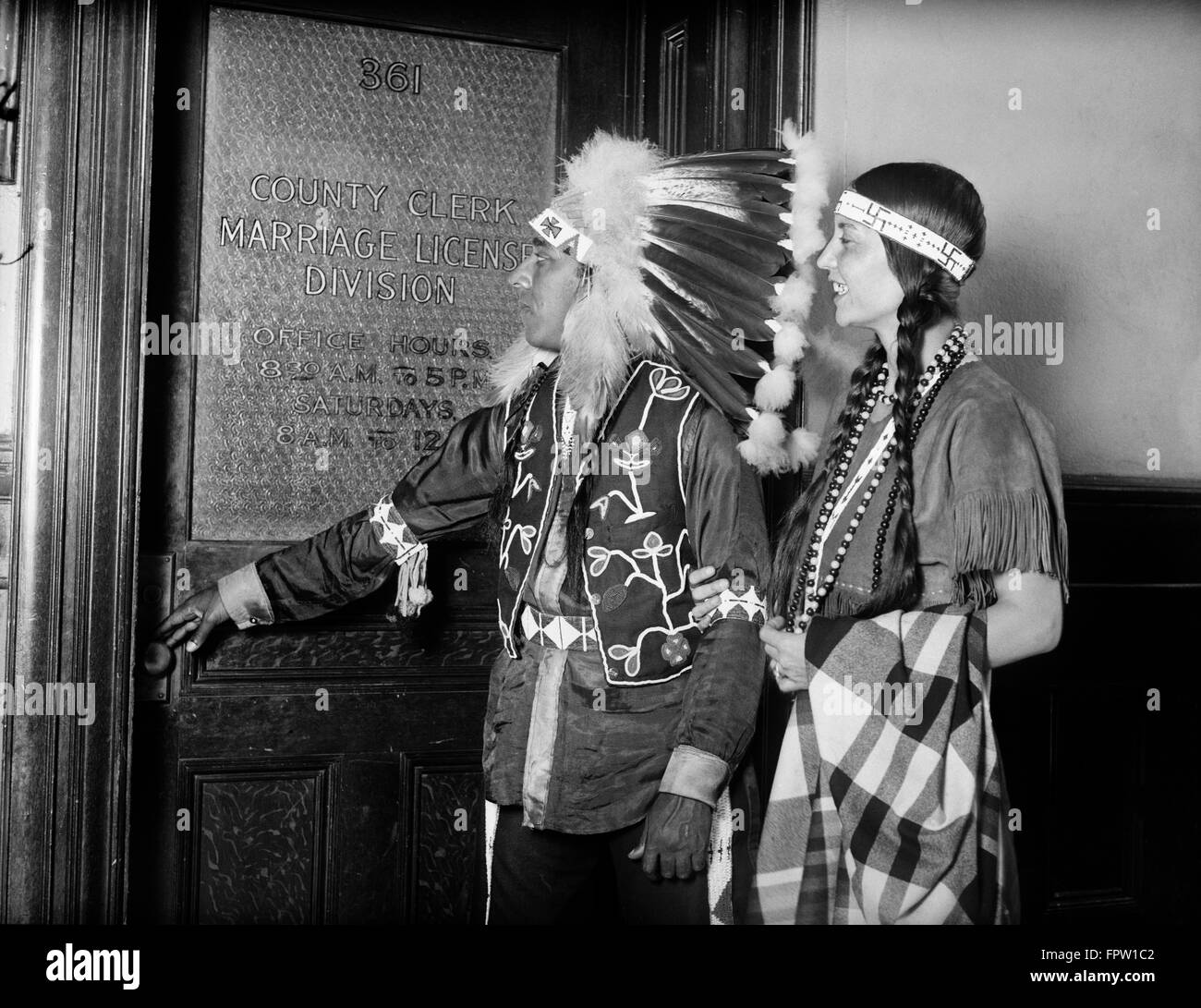 1930ER JAHREN NATIVE AMERICAN INDIAN PAAR TRAGEN TRADITIONELLE KLEIDUNG FEDER KOPFSCHMUCK BEKOMMEN EHE LIZENZ COUNTY CLERK OFFICE Stockfoto