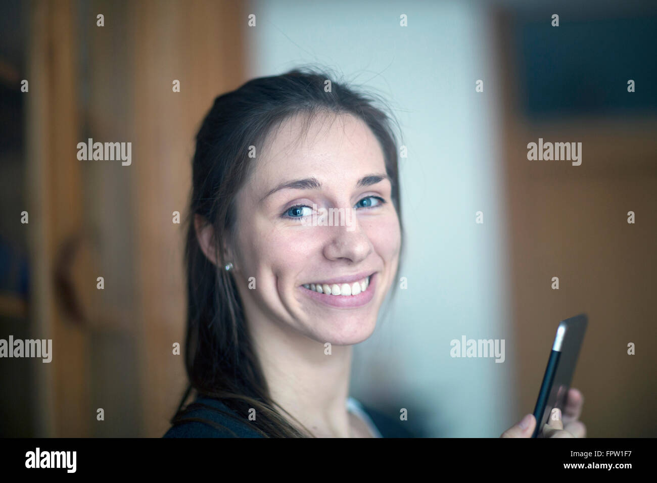 Porträt einer jungen Frau hält digital-Tablette und lächelnd, Freiburg Im Breisgau, Baden-Württemberg, Deutschland Stockfoto