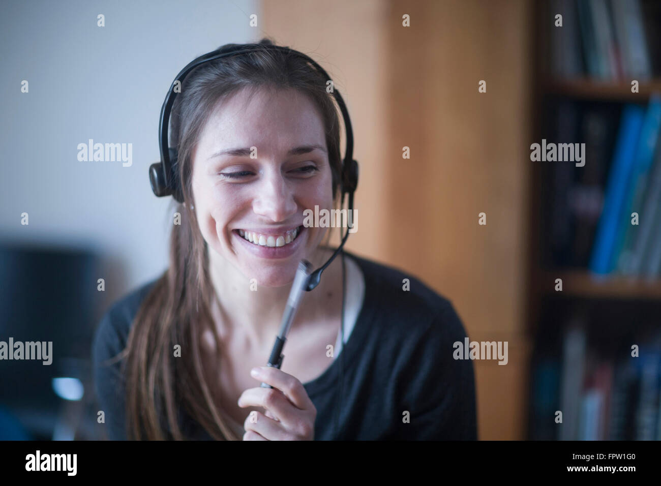 Junge Frau lächelt und spricht über Kopfhörer, Freiburg Im Breisgau, Baden-Württemberg, Deutschland Stockfoto