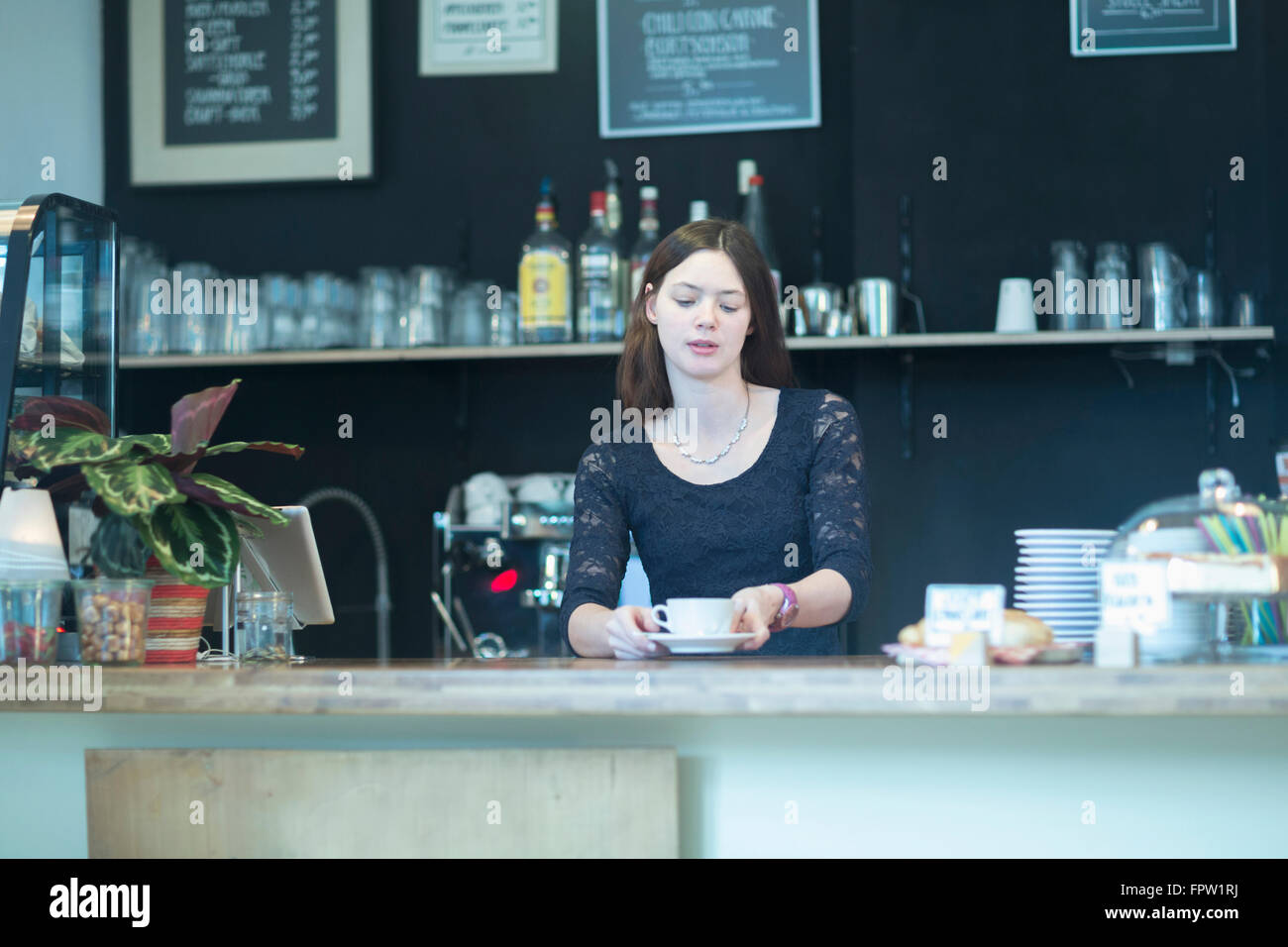 Junge Kellnerin serviert Kaffee in Coffee-Shop, Freiburg Im Breisgau, Baden-Württemberg, Deutschland Stockfoto