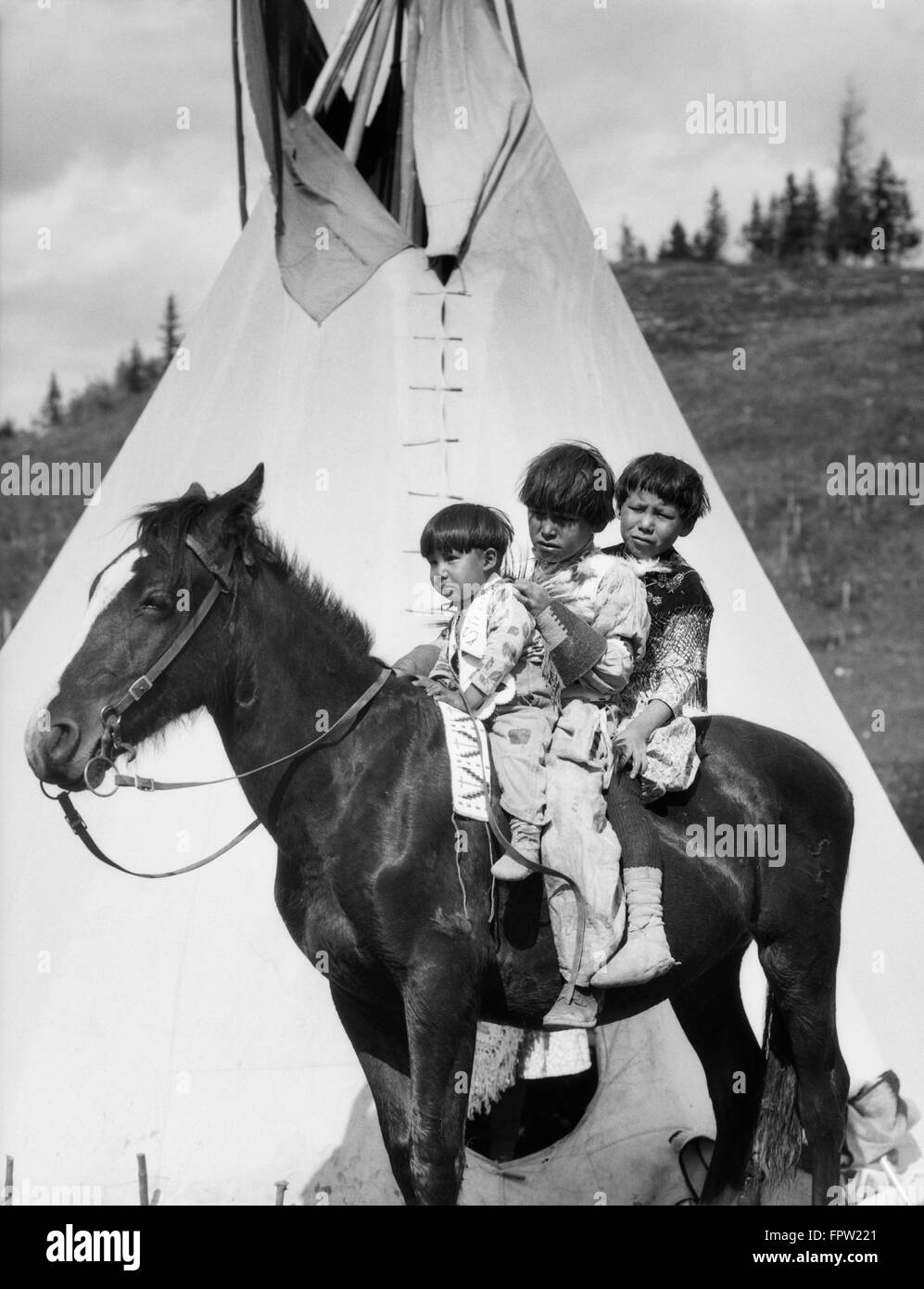 1920ER JAHREN DREI INDIANISCHEN STONEY SIOUX INDISCHE KINDER REITEN AUF PFERD VON TIPI ALBERTA CANADA Stockfoto