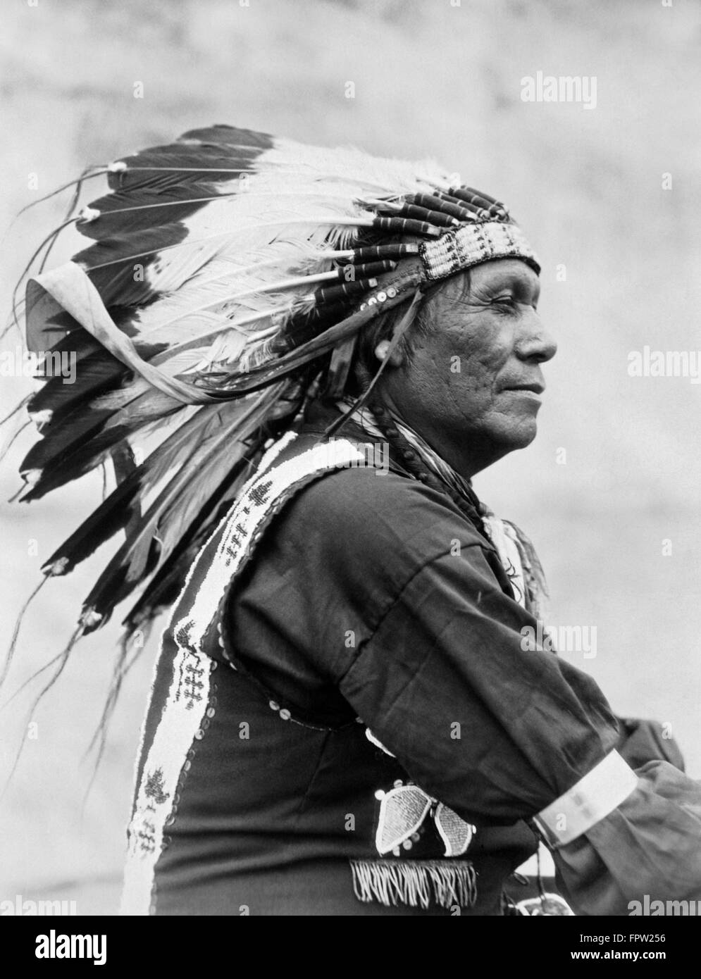1920ER JAHRE PROFIL PORTRAIT INDIANER INDER BLACKFOOT STAMM TRÄGT VOLLE FEDER KOPFSCHMUCK MONTANA USA Stockfoto