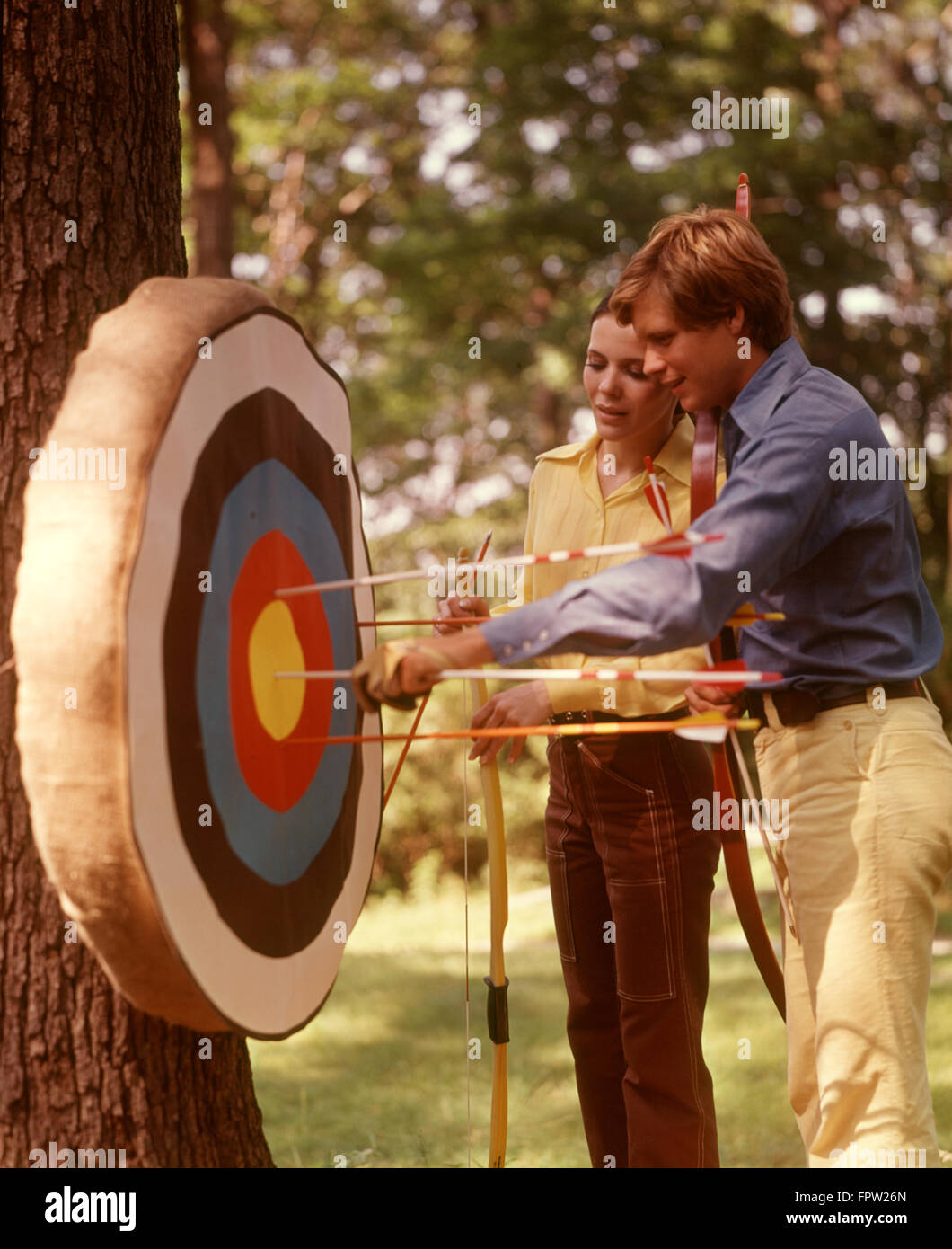 1970ER JAHREN PAAR BOGENSCHIEßEN ZIEL BÖGEN PFEILE ZIELE BOGENSCHÜTZEN PAARE MANN FRAU MÄNNER FRAUEN SPORT BOGEN SPORT Stockfoto