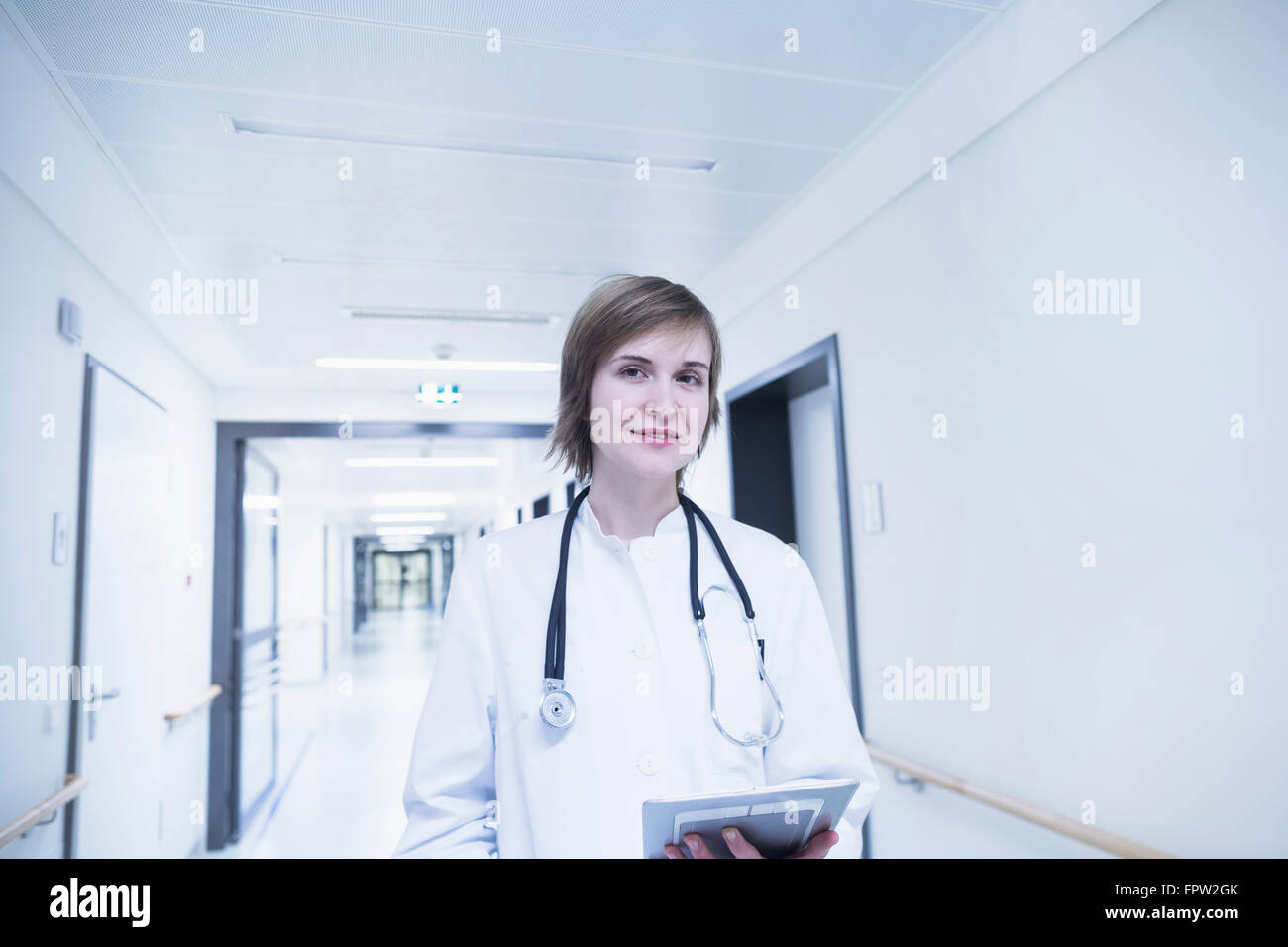 Junge Ärztin hält Zwischenablage im Krankenhausflur, Freiburg Im Breisgau, Baden-Württemberg, Deutschland Stockfoto
