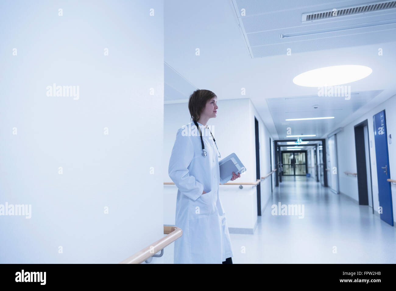 Junge Ärztin hält Zwischenablage und Wandern im Krankenhausflur, Freiburg Im Breisgau, Baden-Württemberg, Deutschland Stockfoto