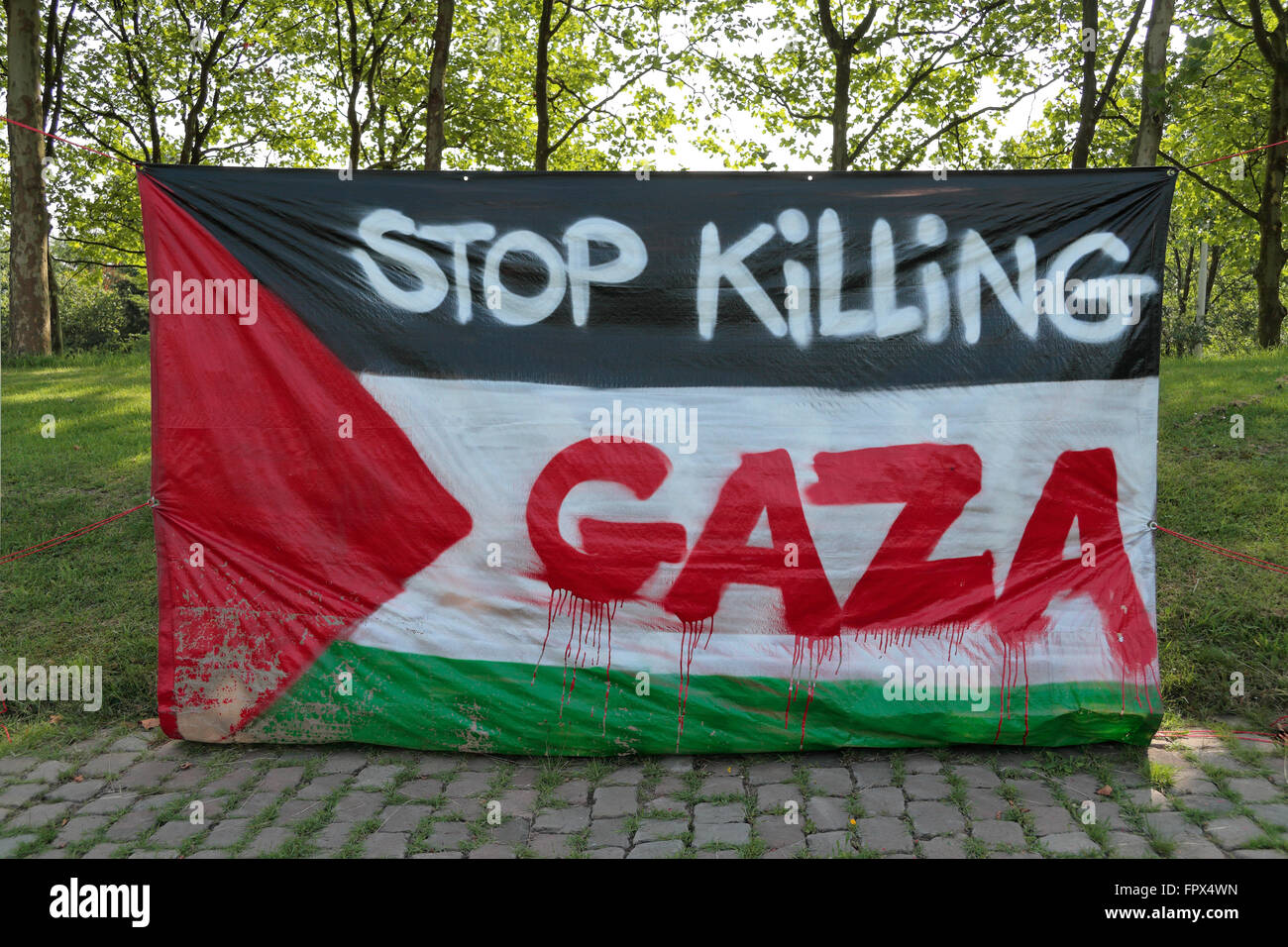 Eine "Stop Killing Gaza" Meldung auf eine palästinensische Flagge am Straßenrand in Nijmegen, Niederlande. Stockfoto