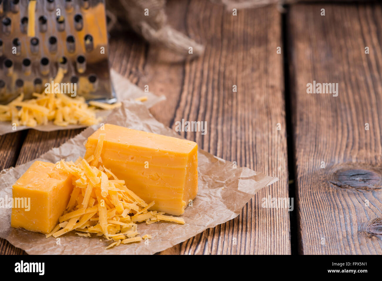 Geriebenen Cheddar-Käse auf rustikalen hölzernen Hintergrund Stockfoto