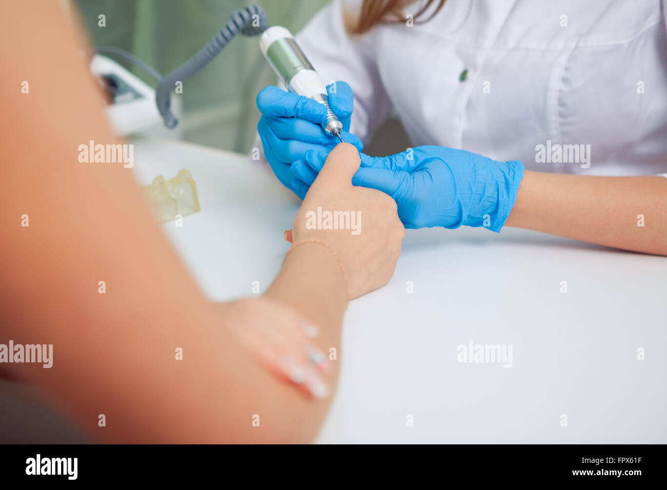 Closeup Aufnahme einer Frau mit einem Nagelhautschieber Nagel Maniküre geben. Nagel-Techniker geben Kunden eine Maniküre im Nagelstudio. Kaukasische Mädchen erhalten eine französische Maniküre. Stockfoto