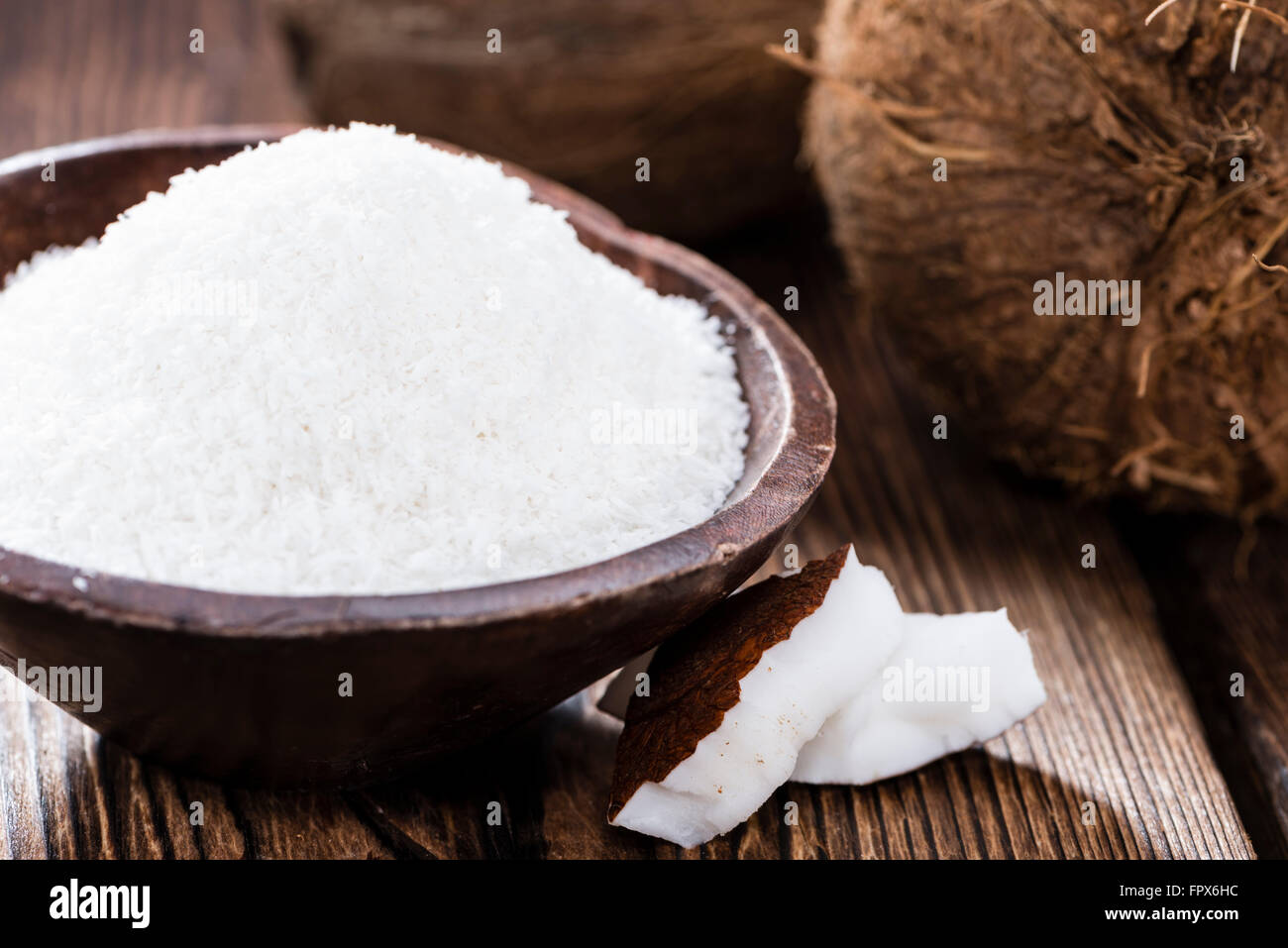 Kokosraspeln (detaillierte Nahaufnahme) auf hölzernen Hintergrund Stockfoto