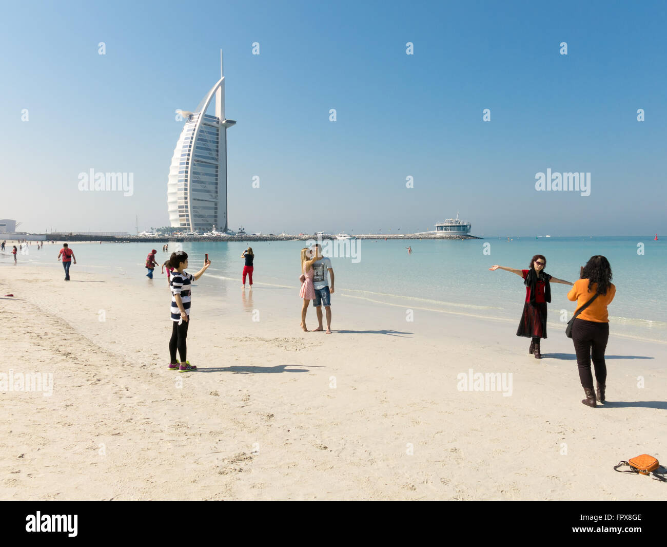 Touristen fotografieren und Selfies am Jumeirah Beach mit Luxushotel Burj al Arab im Hintergrund, Dubai, Vereinigte Arabische Emirate Stockfoto