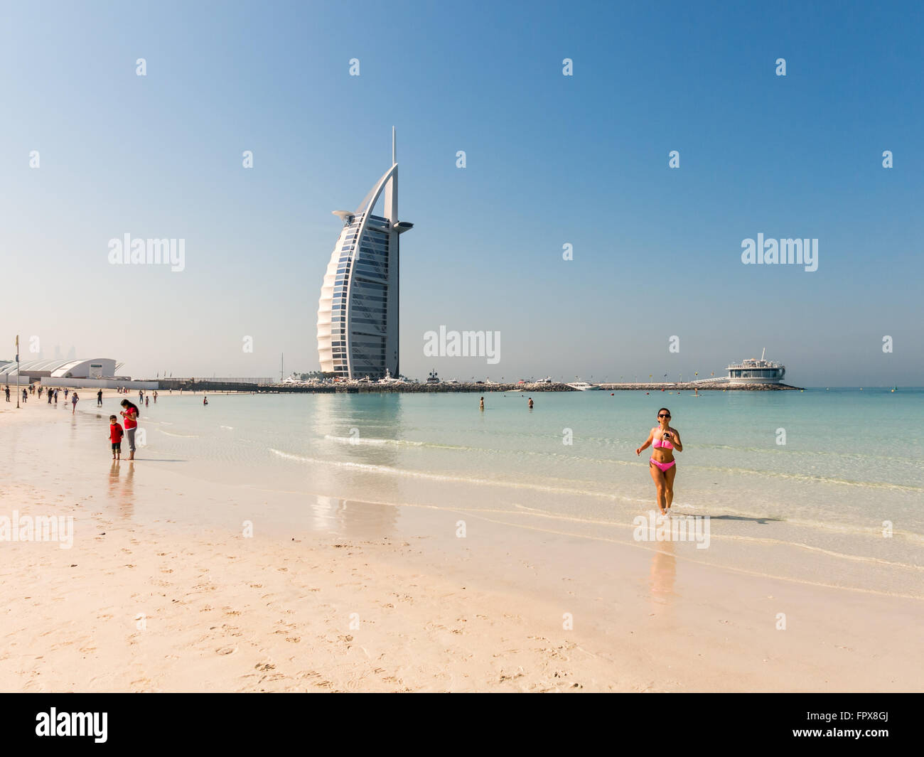 Touristen am Strand von Jumeirah und Burj al Arab Luxushotel im Hintergrund, Dubai, Vereinigte Arabische Emirate Stockfoto