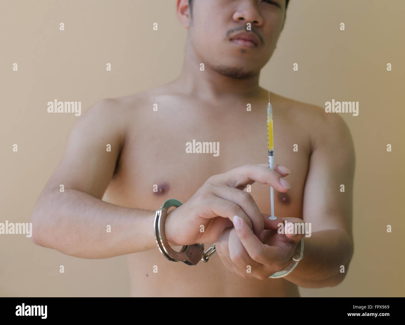 junger Mann hält Syring in der hand mit Handschellen Stockfoto