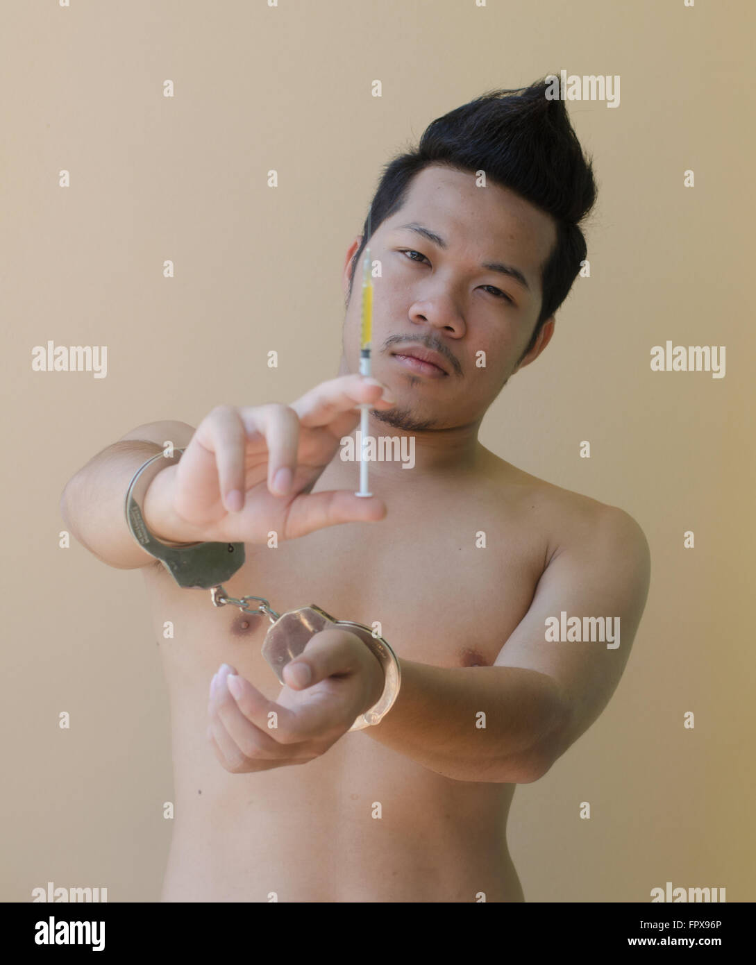 junger Mann hält Syring in der hand mit Handschellen Stockfoto