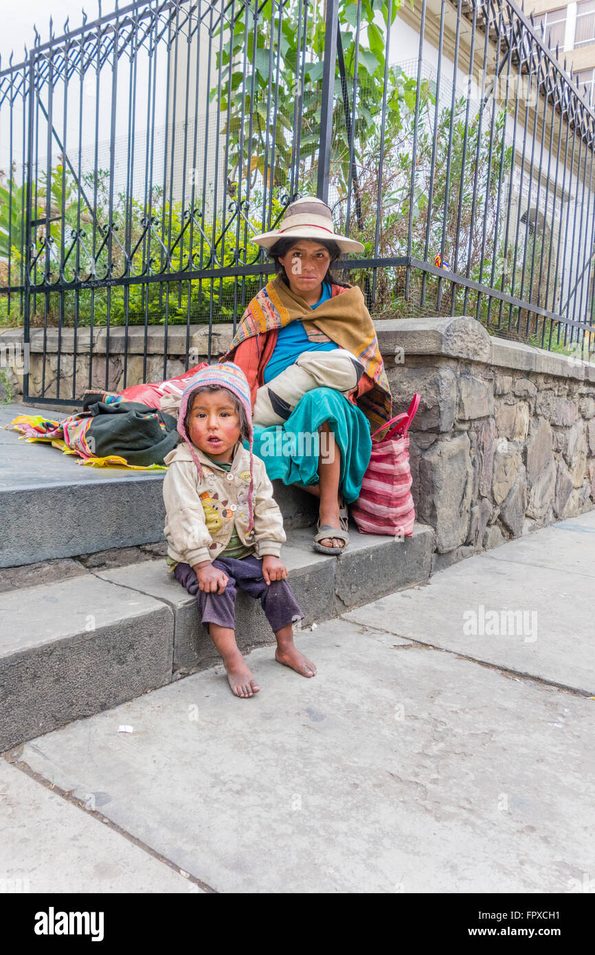 Jungen bolivianischen männlichen Straßenkind, ca. 4-5 Jahre alt, mit seiner Mutter starrt in die Kamera ein Bild von ihm und seine schmutzige Wäsche. Stockfoto