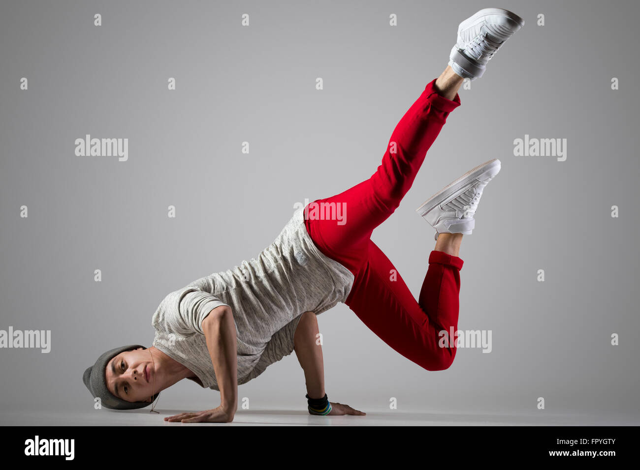 Einer schönen modernen Stil Tänzerin junger Mann in rot Freizeithosen passen und Mütze Ausarbeitung, Durchführung Breakdance Moves, Sta hand Stockfoto