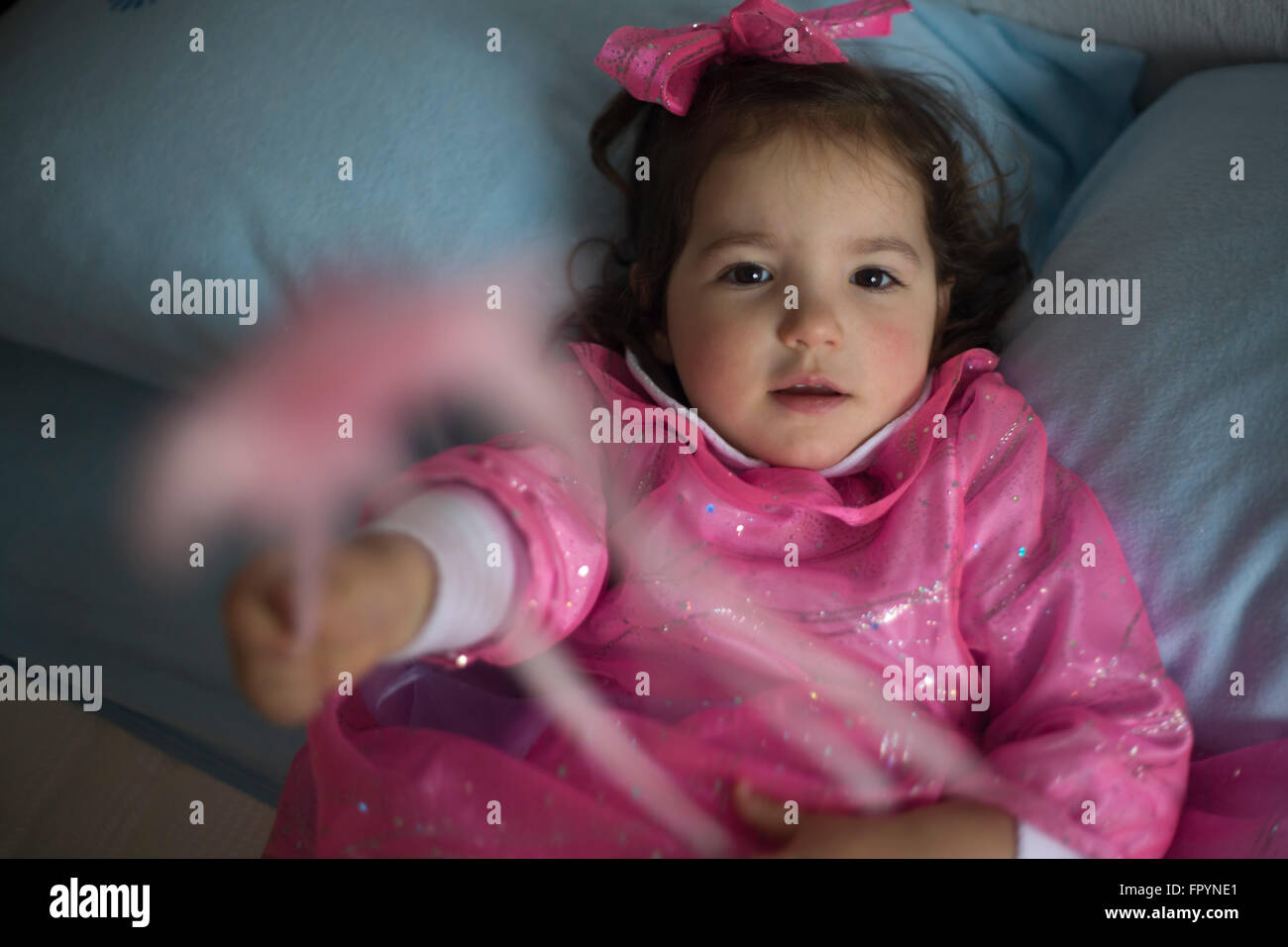 Kleines Mädchen verkleidet als eine Fee mit Zauberstab auf dem Bett sitzen und spielen Stockfoto