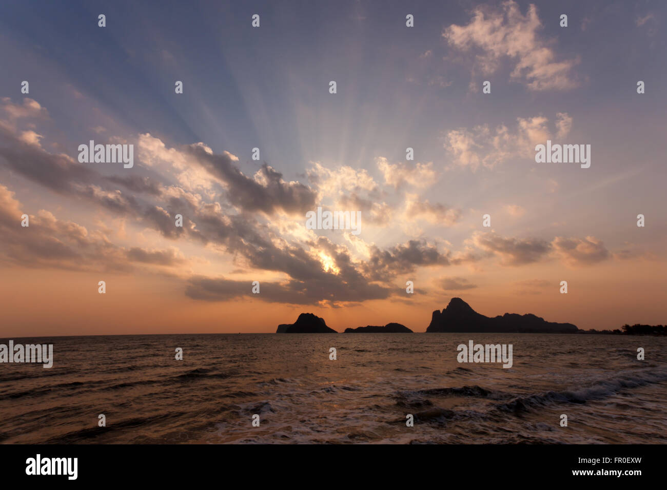 Strand-Sonnenaufgang oder Sonnenuntergang. Sonne durch die Wolken. Stockfoto