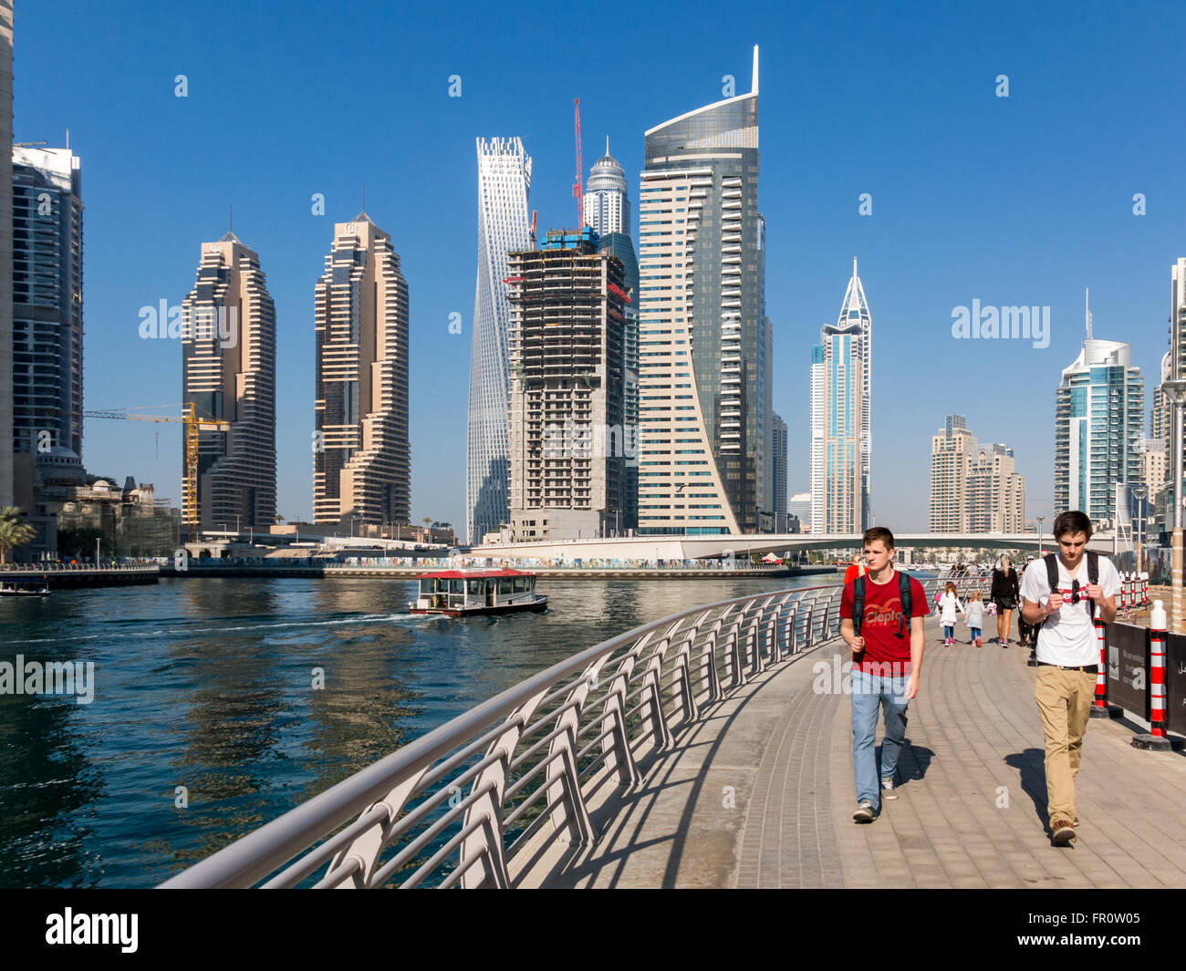 Menschen zu Fuß auf der Promenade mit Wasser Hochhäuser im Marina District von Dubai, Vereinigte Arabische Emirate Stockfoto