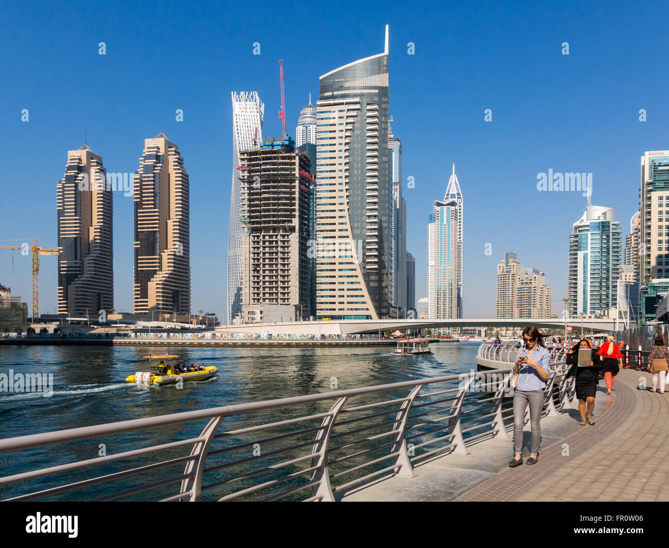 Menschen zu Fuß auf der Promenade, Boote und Highrise Gebäude im Stadtteil Marina von Dubai, Vereinigte Arabische Emirate Stockfoto