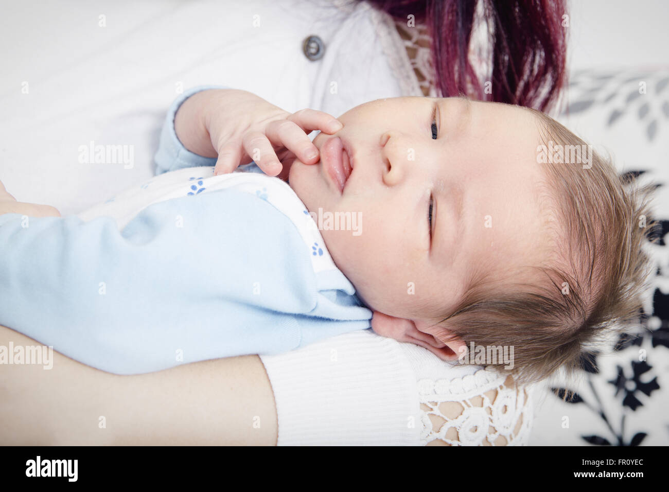 Junge Mutter mit ihrem Sohn in die Arme. Nahaufnahme des Neugeborenen in Umarmungen von seiner Mutter schlafen. Einen Monat alt Baby Boy in Comfor Stockfoto