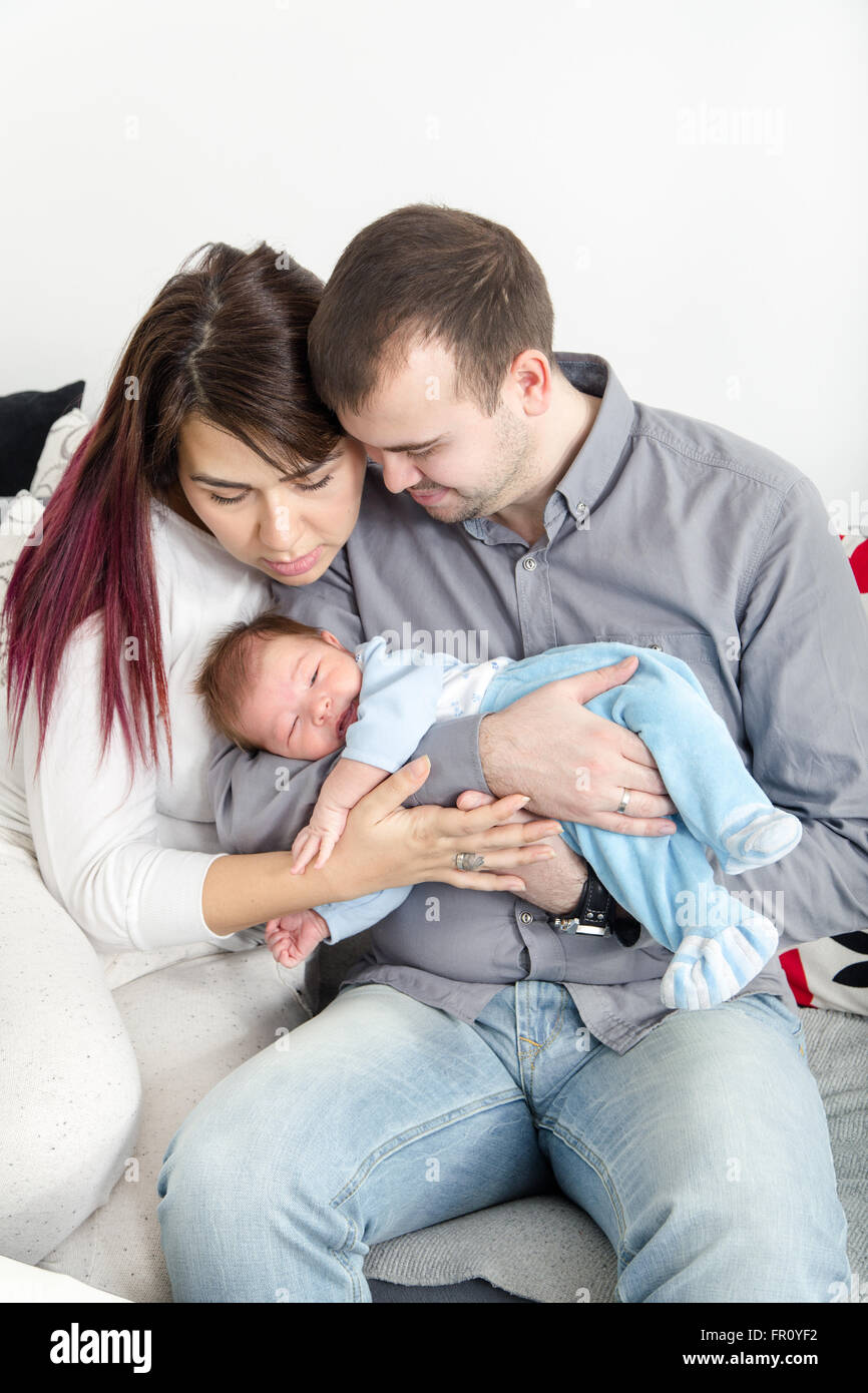 Junge schöne Paar mit neuen Baby zu Hause. Porträt einer lächelnden glücklichen Familie mit dem Kind im inländischen hellen Hintergrund. Mann Stockfoto