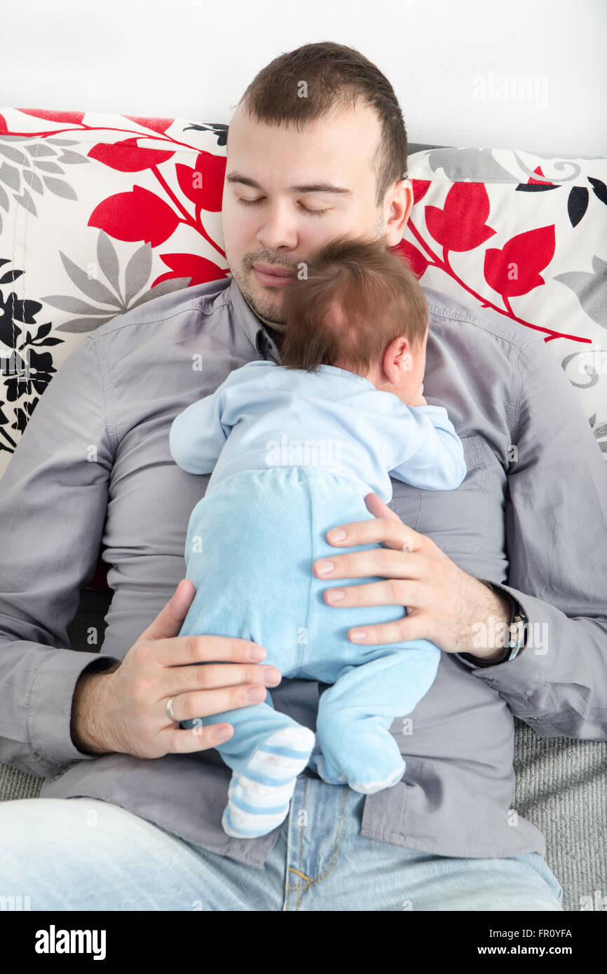 Junger Vater und seinem kleinen Jungen zusammen. Papa mit seiner fröhlichen Neugeborenen auf Sofa gute Zeit nehmen. Inländische Familie. Closeup Stockfoto