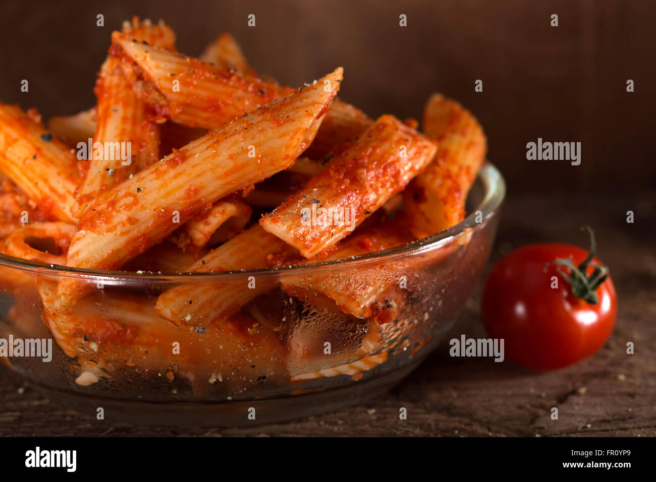 Penne-Nudeln in Tomatensauce mit Fleisch und Tomaten auf einem hölzernen Hintergrund Stockfoto