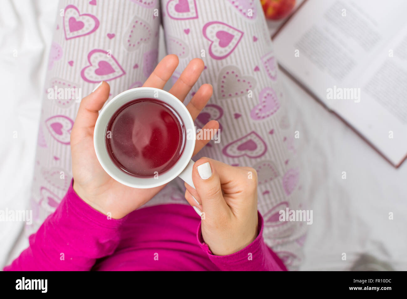 Frau mit einer Tasse Früchtetee im Bett Stockfoto