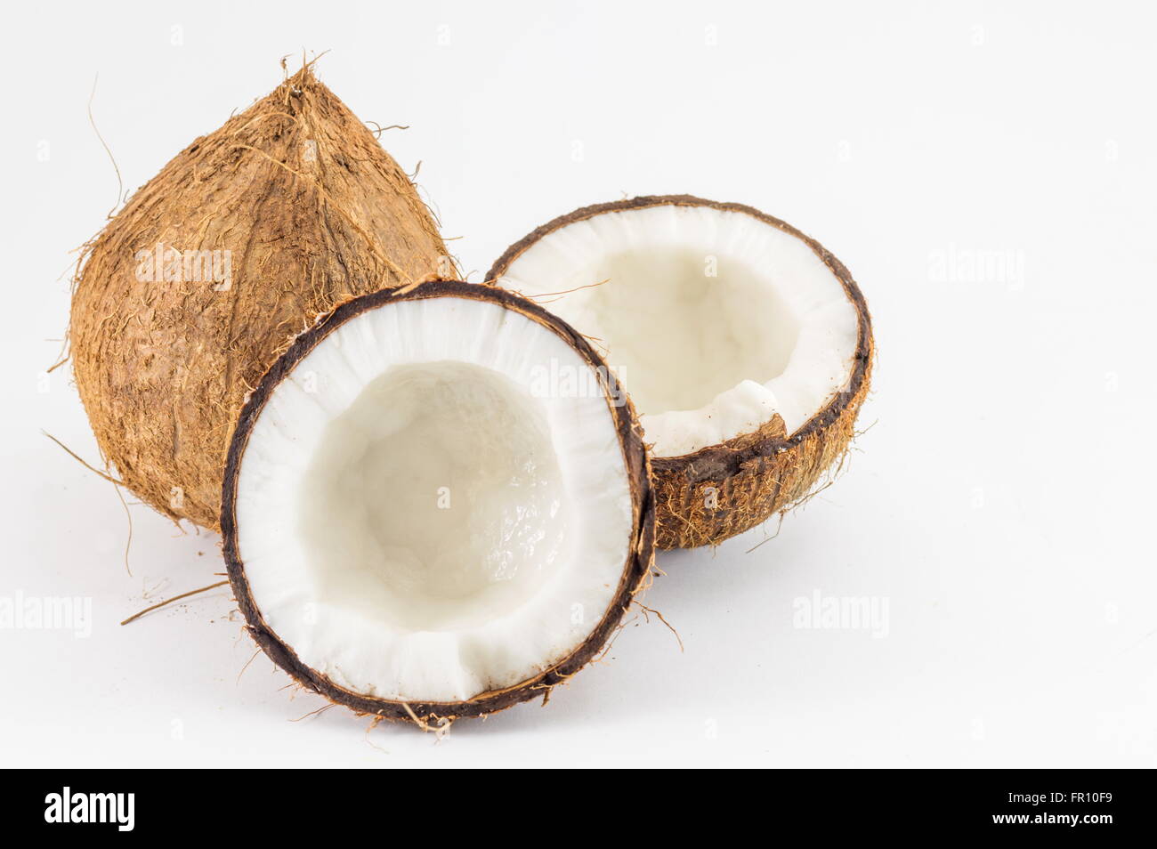 Halbierte und ganze frische Kokosnüsse mit Kokosnuss lässt auf weiß Stockfoto