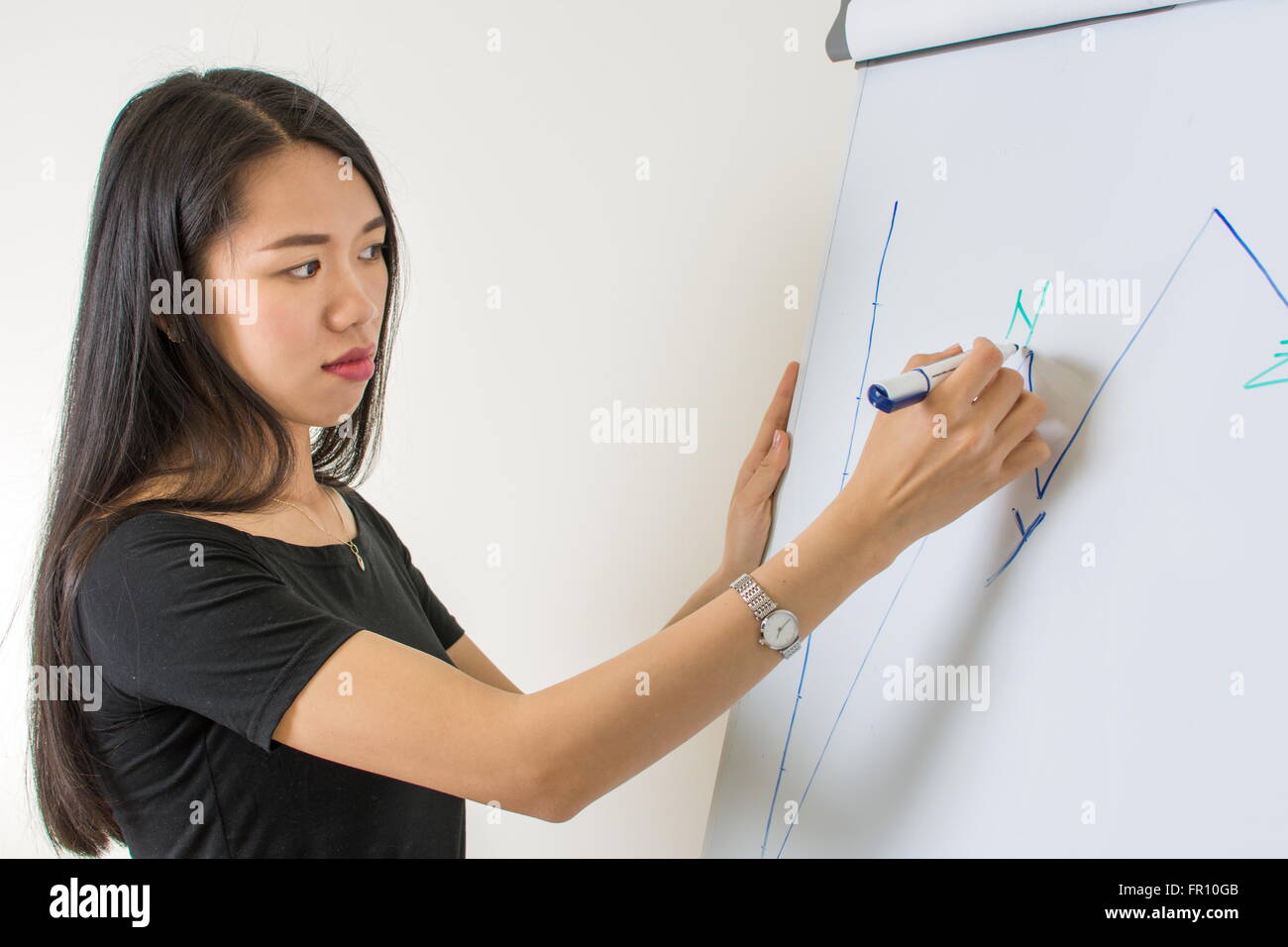 Junge asiatische Frau, die auf ein Flipchart schreiben Stockfoto