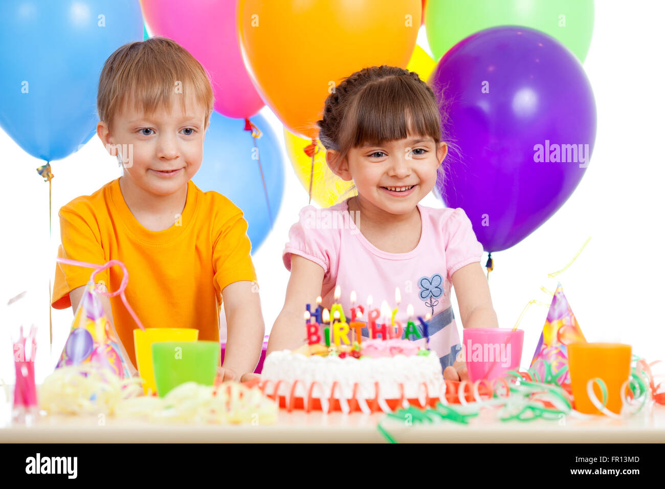 Lächelnde kleine Jungen und Mädchen mit Geburtstag Kuchen und Farbe ballons Stockfoto