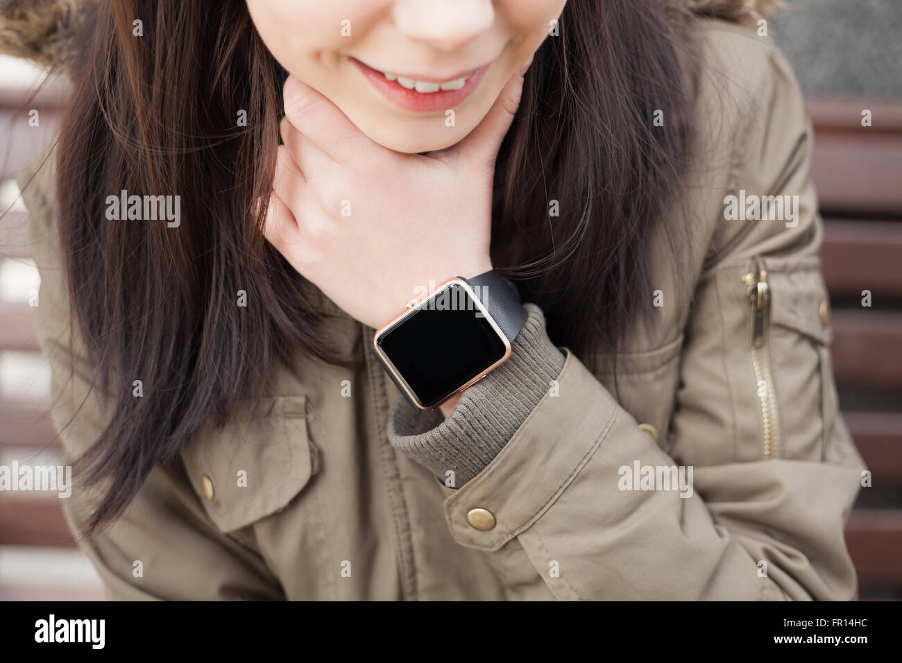 Lächelnde junge Mädchen tragen trendige intelligente Armbanduhr im Freien. Neue Technologie in realen Szenario. Stockfoto