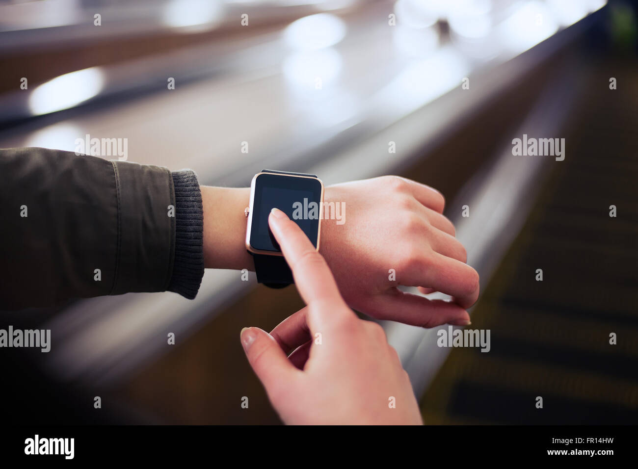 Weibchen mit ihrem trendigen smart Handgelenk sehen während der Fahrt mit u-Bahn Rolltreppe. Diese Person ist immer mit social Media und Internet verbunden. Stockfoto