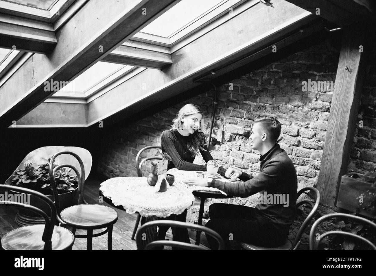 Schöne stilvolle Pärchen in einem roten Kleid in Liebesgeschichte im Vintage Café mit großen Fenstern und am Dach Stockfoto