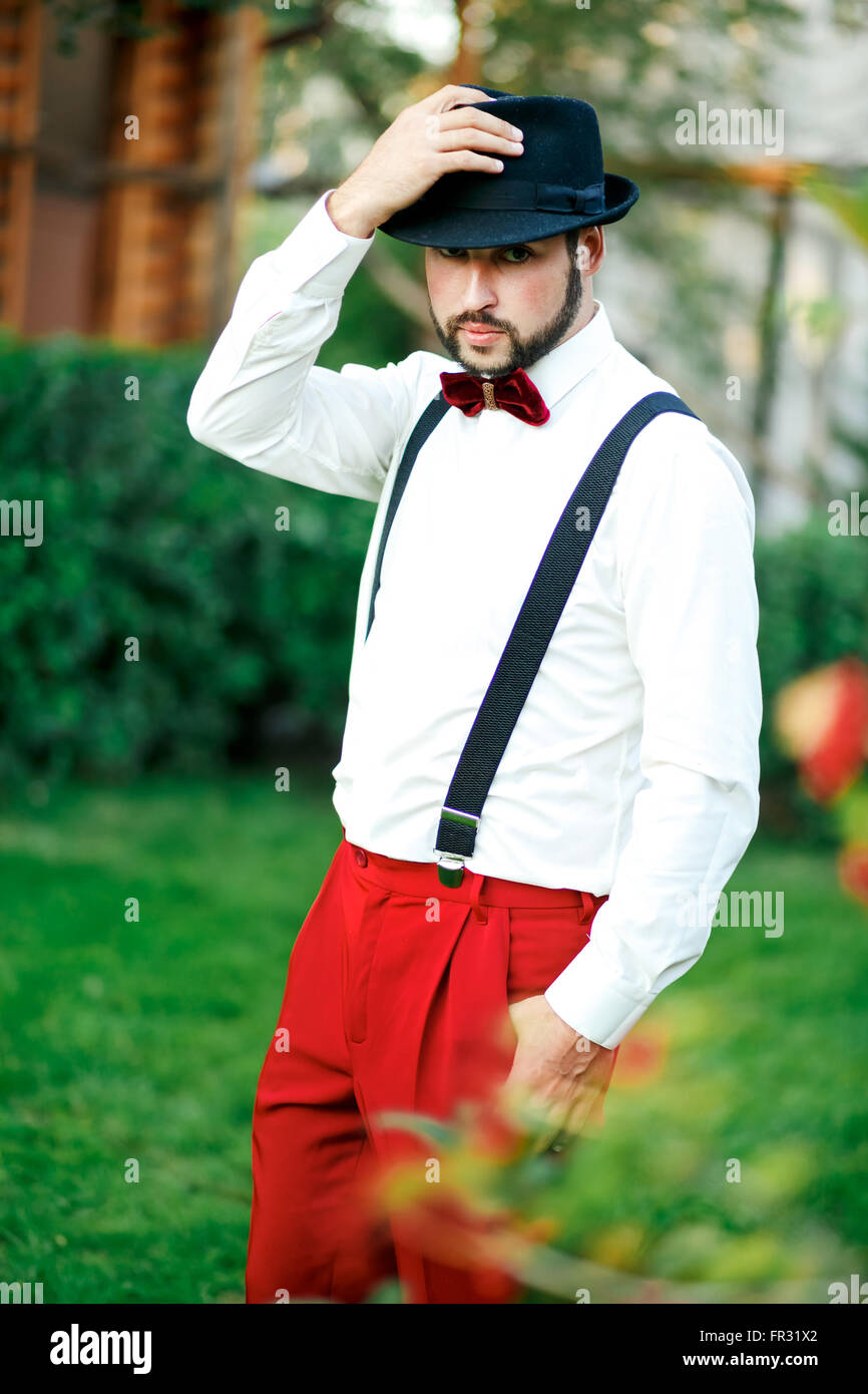 Macho Mann in Hut und roten Hosen mit Hosenträgern. Stockfoto